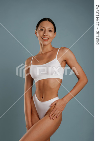 Fitness model is in white underwear. Young woman is in the studio against background 134413542