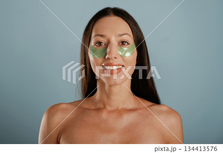 Against background. Eye patches. Young woman is in the studio Against background. Eye patches. Young woman is in the studio 134413576