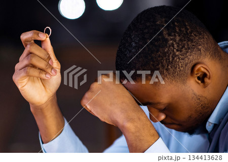 Woman leaving upset black boyfriend after rejecting marriage proposal. Depressed african american guy sitting at table with ring in hand, feeling lonely and abandoned, cropped image, selective focus Woman leaving upset black boyfriend after rejecting marriage proposal. Depressed african american guy sitting at table with ring in hand, feeling lonely and abandoned, cropped image, selective focus 134413628