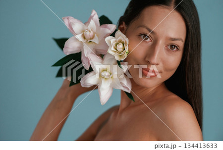 With lily flower. Young woman is in the studio against background 134413633