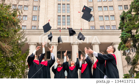 International group of students standing in a row and throwing graduation caps up in the air, posing next to university building after graduation ceremony, celebrating freedom International group of students standing in a row and throwing graduation caps up in the air, posing next to university building after graduation ceremony, celebrating freedom 134413711