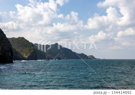 切り立った海岸と緑の山並みを背に広がる波だった青い海 切り立った海岸と緑の山並みを背に広がる波だった青い海 134414092