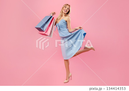 Full length portrait of pretty young lady with shopping bags feeling happy, purchasing gifts for spring holiday on pink studio background. Lovely blonde with presents for special occassion Full length portrait of pretty young lady with shopping bags feeling happy, purchasing gifts for spring holiday on pink studio background. Lovely blonde with presents for special occassion 134414353