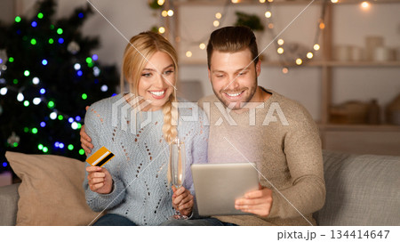 Happy couple doing Christmas shopping together, using digital tablet and credit card, copy space Happy couple doing Christmas shopping together, using digital tablet and credit card, copy space 134414647