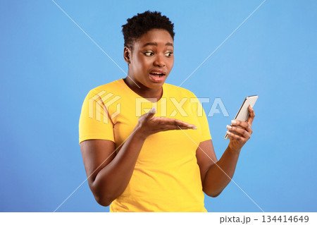 Discontented Black Lady Holding Smartphone Having Problem With Mobile Phone Or Waiting For Call Standing Over Blue Studio Background. Displeased Female Showing Cellphone Concept Discontented Black Lady Holding Smartphone Having Problem With Mobile Phone Or Waiting For Call Standing Over Blue Studio Background. Displeased Female Showing Cellphone Concept 134414649