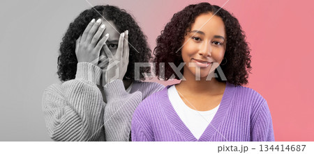Happy, scared, sad millennial black lady feeling bad, cover face with hands on pink and gray background, studio, panorama. Mental problems, stress emotions, pms mood and depression 134414687
