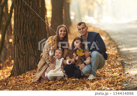 Sitting, posing. Happy family of mother, father and two daughters are in the autumn park, forest, road 134414898