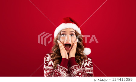 Christmas celebration. Excited young woman in Santa hat and warm winter sweater over red background. Panorama Christmas celebration. Excited young woman in Santa hat and warm winter sweater over red background. Panorama 134415089