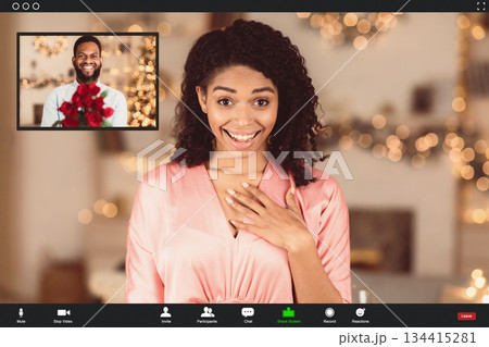 Long Distance Relationship. Surprised african american woman in dress making online video call with boyfriend who showing red roses to webcam during videochat. Screen view with conference app 134415281
