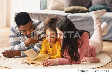 Reading lessons in an international family on the floor at home during covid-19 quarantine Reading lessons in an international family on the floor at home during covid-19 quarantine 134415311