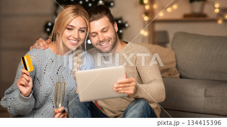 Happy couple doing some shopping together on digital tablet on xmas eve, using credit card, copy space Happy couple doing some shopping together on digital tablet on xmas eve, using credit card, copy space 134415396