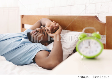 Sleep disorder. Young african-american guy in bed suffering from insomnia, thinking about his problems at night, copy space Sleep disorder. Young african-american guy in bed suffering from insomnia, thinking about his problems at night, copy space 134415507