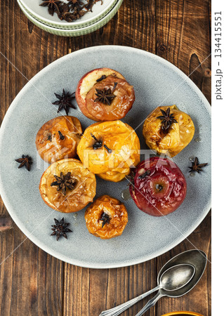 Baked apples with spices on wooden surface. 134415551