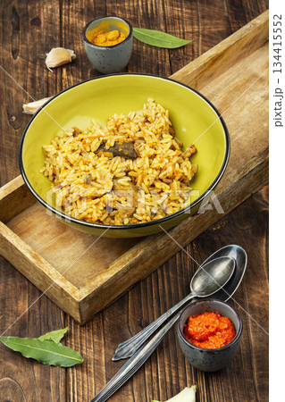 Traditional rice pilaf with meat on wooden surface. 134415552