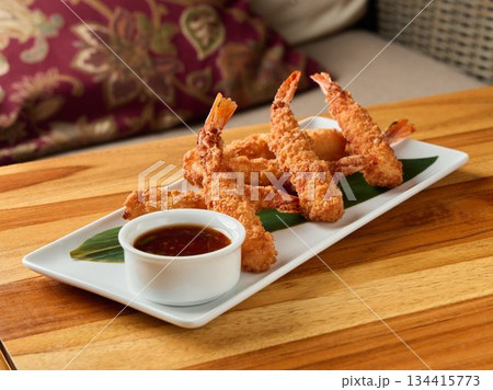 Delicious crispy shrimp tempura presented on rectangular dish alongside savory dipping sauce 134415773