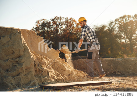 The soil, digging with shovel. Worker is on the construction site at daytime The soil, digging with shovel. Worker is on the construction site at daytime 134415899