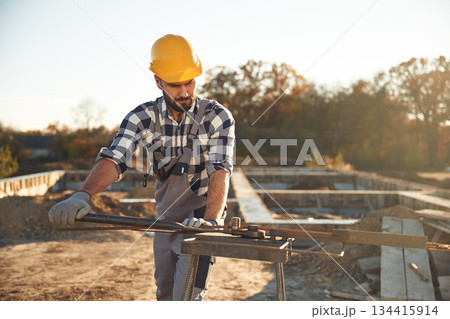 Some metal job with a rod. Worker is on the construction site at daytime 134415914