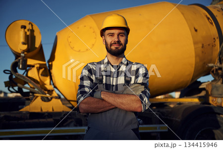 Against concrete mixer truck. Worker is on the construction site at daytime Against concrete mixer truck. Worker is on the construction site at daytime 134415946