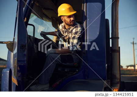 Construction worker is sitting in the truck cabin Construction worker is sitting in the truck cabin 134415951
