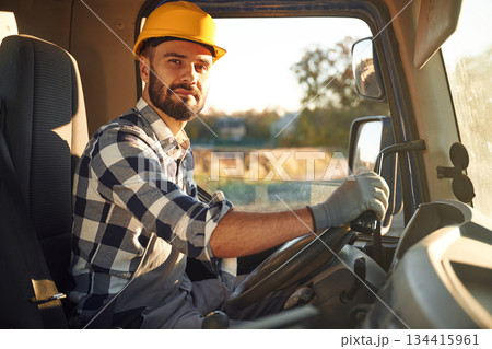 Construction worker is sitting in the truck cabin Construction worker is sitting in the truck cabin 134415961