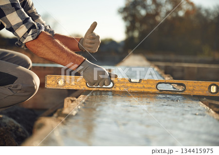 Leveler tool. Close up view of worker on the construction site Leveler tool. Close up view of worker on the construction site 134415975