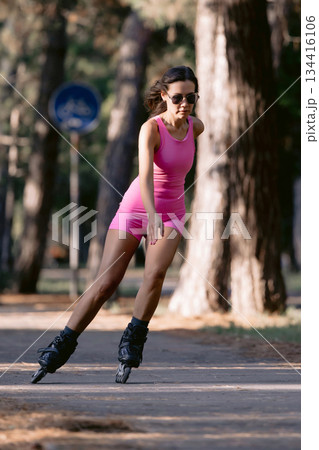 Woman in pink sportwear roller skating in the park, active lifestyle concept. 134416106