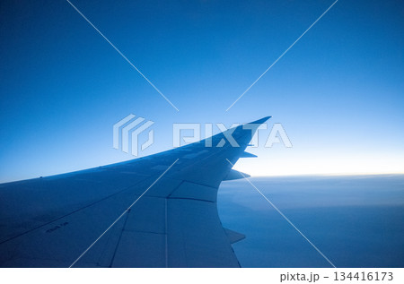 飛行機の窓側席から望む航空機の翼と広がる青空と水平線 飛行機の窓側席から望む航空機の翼と広がる青空と水平線 134416173