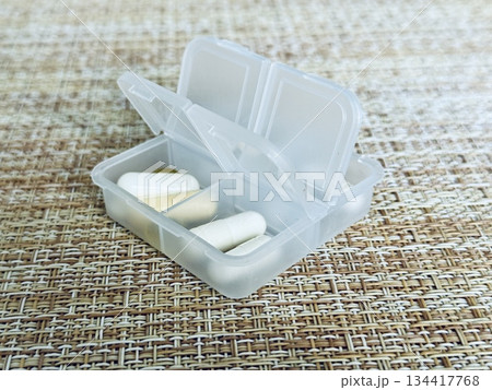 The weekly transparent pillbox is designed for convenient and efficient daily storage of dietary supplements and tablets. It has compartments with various types of capsules for administration. 134417768