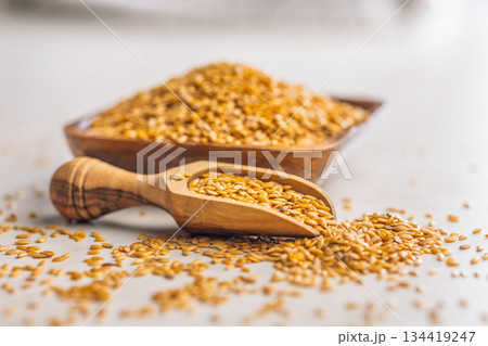 Golden linseed or flaxseed. Healthy flax seed in wooden scoop on kitchen table. Golden linseed or flaxseed. Healthy flax seed in wooden scoop on kitchen table. 134419247