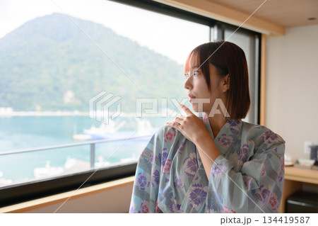 窓辺で海を眺める浴衣の女性 134419587