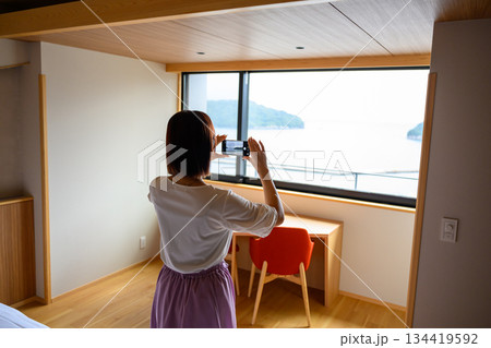ホテル客室から海を撮影する女性 134419592