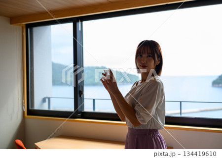窓辺でスマホを操作する女性 134419610