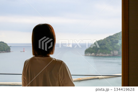 窓から海を眺める女性の後ろ姿 134419628