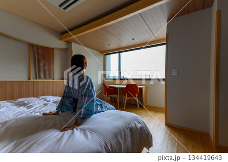 浴衣姿の女性、ホテル客室で窓外を望む 134419643