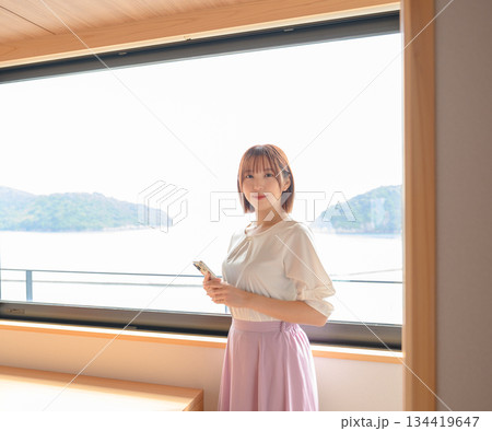 ホテルでスマホを持つ女性と窓外の景色 134419647