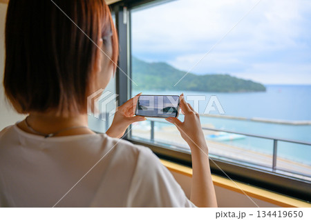 スマホで窓外の島を撮影する女性 134419650