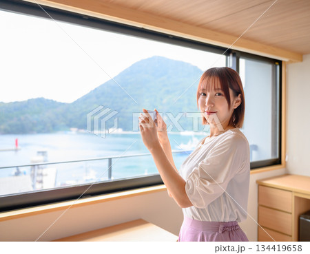 ホテル客室から外の景色を撮影する女性 134419658