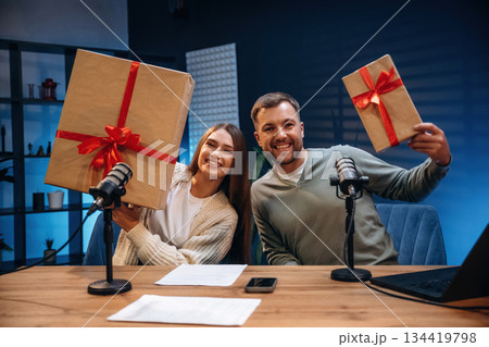 Happy, holding new year gift boxes. Radio hosts recording podcast 134419798