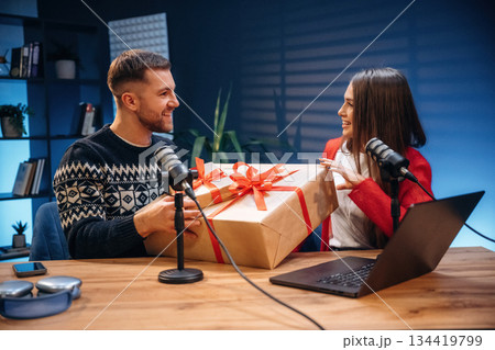 Happy, holding new year gift boxes. Radio hosts recording podcast Happy, holding new year gift boxes. Radio hosts recording podcast 134419799