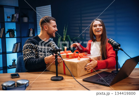 Happy, holding new year gift boxes. Radio hosts recording podcast Happy, holding new year gift boxes. Radio hosts recording podcast 134419800