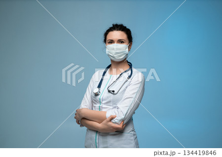 Female doctor in medical mask and protective glasses posing confidently in uniform 134419846