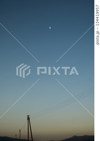 広大なグラデーションの空を横切る電線と月 134419957