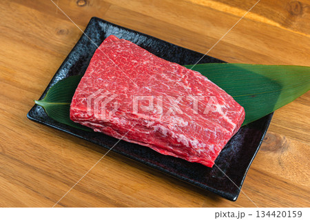 牛肩肉のブロック 生肉の食材写真 黒い器と木目テーブル 134420159