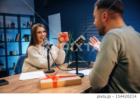 Woman is holding Christmas gift box. Radio hosts recording podcast 134420214