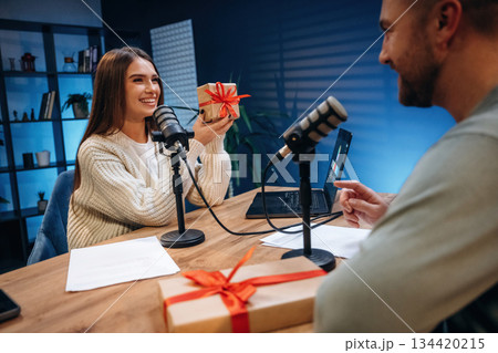 Woman is holding Christmas gift box. Radio hosts recording podcast 134420215