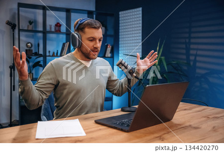 By the laptop. Man with microphone in the studio, conception of podcast 134420270