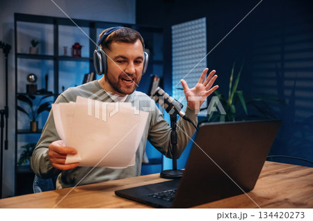 By the laptop. Man with microphone in the studio, conception of podcast 134420273