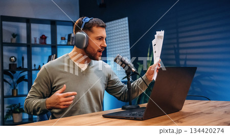 By the laptop. Man with microphone in the studio, conception of podcast 134420274
