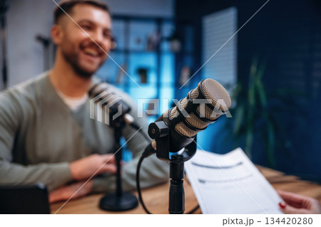 Sitting and smiling. Man with microphone in the studio, conception of podcast Sitting and smiling. Man with microphone in the studio, conception of podcast 134420280