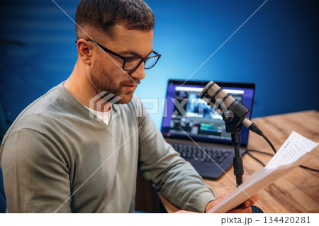 Reading the text. Man with microphone in the studio, conception of podcast Reading the text. Man with microphone in the studio, conception of podcast 134420281